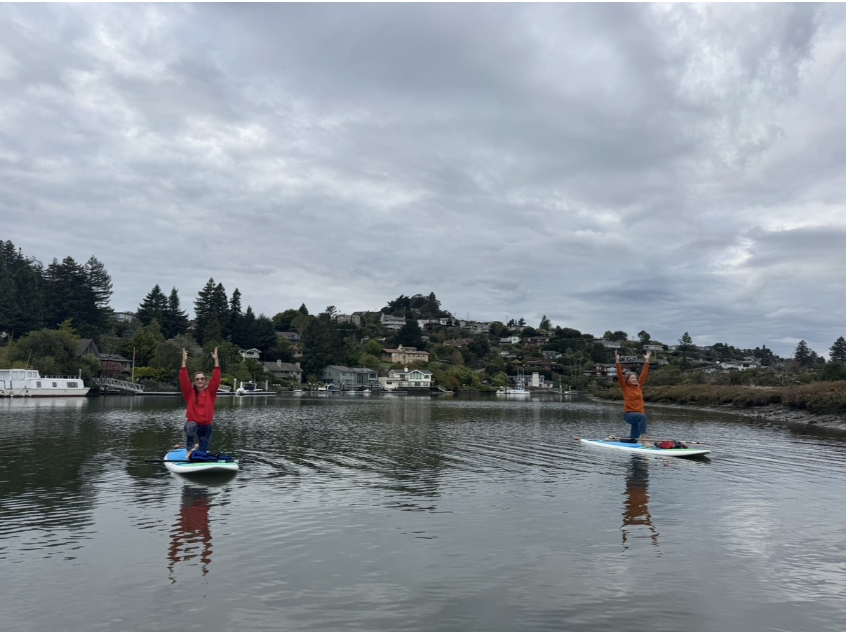 Two paddlers in tree pose on the lagoon
